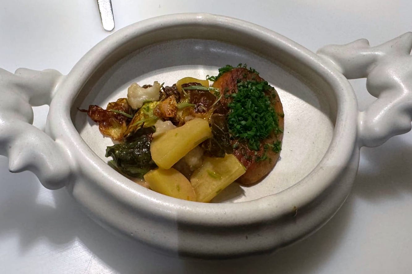 Char-grilled king oyster mushroom styled like an Augsburger sausage, sliced with browned edges and herb seasoning.